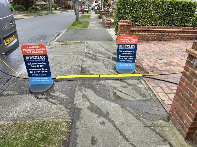 Bexley Power Washing branded signage and hoses set up on a driveway cleaning job