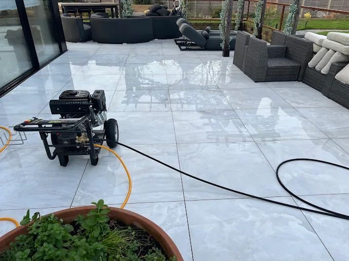 Large-format grey porcelain patio slabs pressure washed to a glossy finish