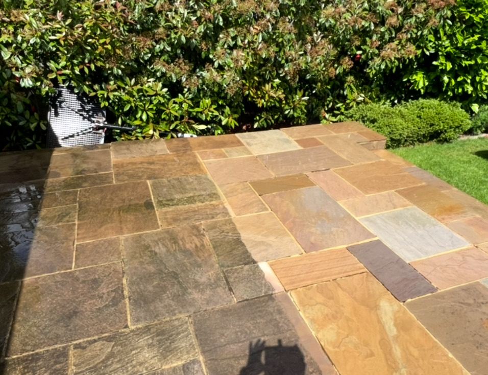 Indian sandstone patio mid-clean, with the washed side showing its original golden colour next to the darker unwashed stone